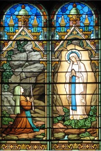 Vitrail au-dessus de l’entrée de l’église représentant les apparitions de Marie à Bernadette à Lourdes – paroisse de Saint Genis Laval