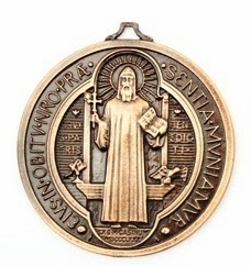 Saint Benoît est représenté au centre de la médaille. Dans sa main droite, il tient une croix. La croix représente la puissance salvatrice du Christ et l’œuvre d’évangélisation accomplie par les bénédictins tout au long des siècles. Dans sa main gauche, un livre contenant la sainte Règle de son ordre.  